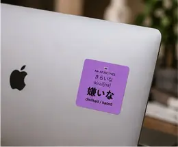 A 嫌いな (kirai[na], disliked/hated) vocabulary sticker on the back of a laptop near the Apple logo