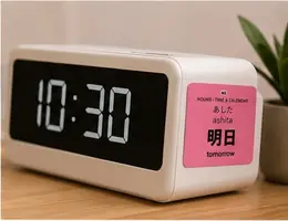 A 明日 (ashita, tomorrow) vocabulary sticker on a digital alarm clock