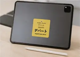 A デパート (depaato, department store) vocabulary sticker on the back of a tablet next to a stylus