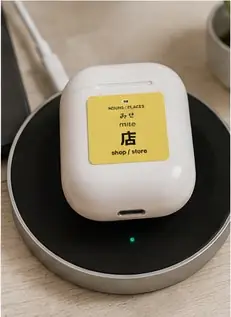 A 店 (mise, shop/store) vocabulary sticker on wireless earbuds in their charging case