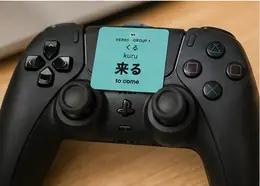 A 来る (kuru, to come) verb sticker on a black game controller
