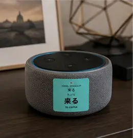 A 来る (kuru, to come) vocabulary sticker on a smart speaker on a shelf