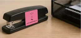 A へ (e, direction marker) particle sticker on a black desktop stapler