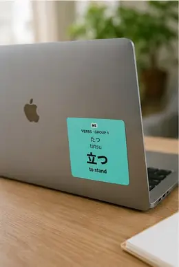 A 立つ (tatsu, to stand) vocabulary sticker on the back of a laptop lid